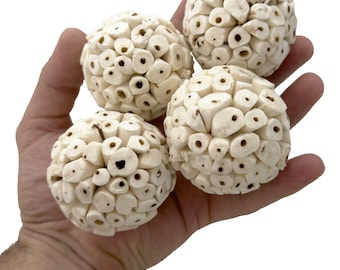 May include: Four decorative, off-white spheres with a textured surface, each composed of small, cylindrical pieces. The spheres are held in a hand against a white background. The spheres have small, dark holes.