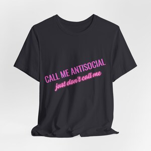Könnte beinhalten: Schwarzes T-Shirt mit dem Text "CALL ME ANTISOCIAL just don't call me" in pinker Neon-Schrift.
