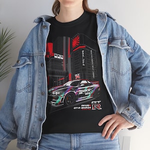 May include: Black t-shirt with a graphic of a sports car, featuring the text "87 HKS SUPER OIL" and "GT-R". The design includes a cityscape with Japanese text and a rising sun. The shirt has a crew neck.