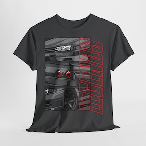 May include: A dark gray t-shirt with a graphic design of three different Nissan Skyline cars. The text "LEGENDS" is printed vertically in red on the right side of the shirt.