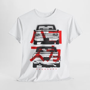 May include: White t-shirt with a black and white illustration of two vintage Japanese cars. The cars are outlined in red and the text "Hakosuka" is printed below the cars.