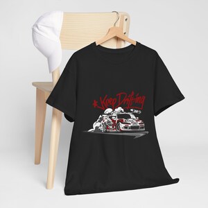 May include: Black t-shirt with a white and red illustration of a car drifting with smoke coming from the tires. The text "Keep Drifting" is written in red above the car.