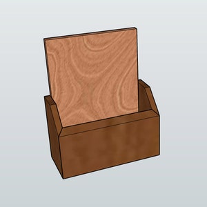 May include: A wooden box with a slanted front opening, designed to hold a single piece of paper or card. The box is made of brown wood with a natural wood grain finish.
