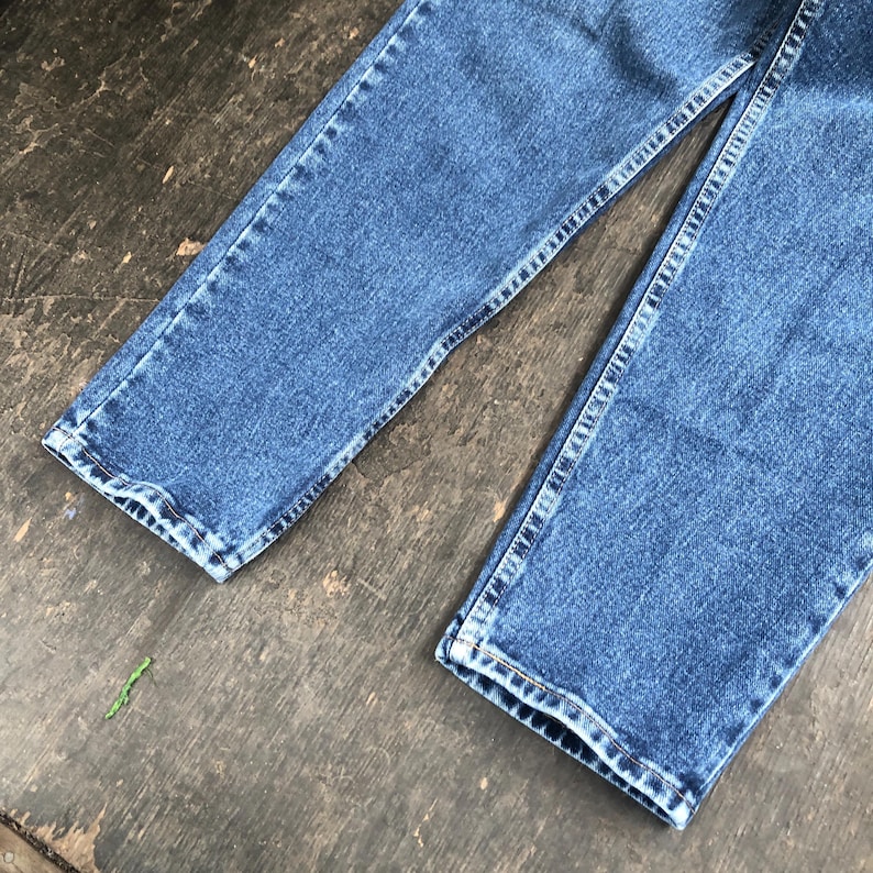 Op de afbeelding: Close-up van een blauwe spijkerbroek. De jeans heeft een klassieke rechte pijp met zichtbare stiksels langs de naden en zomen. De denim heeft een medium wassing en de afbeelding toont het onderste deel van de broek.