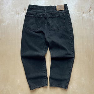Peut inclure: Un jean en denim noir avec une taille haute et une conception classique &agrave; cinq poches. Le jean a une jambe droite et un patch en cuir sur la ceinture arri&egrave;re. Le denim semble &ecirc;tre pr&eacute;-usag&eacute;.