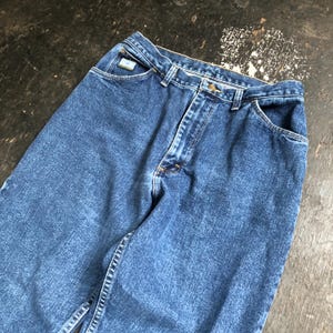 Op de afbeelding: Een spijkerbroek van blauwe denim. De jeans heeft een klassiek ontwerp met vijf zakken, een knoop- en ritssluiting en een kleine logopatch op de voorzak. De denim heeft een medium wassing met subtiele vervaging.
