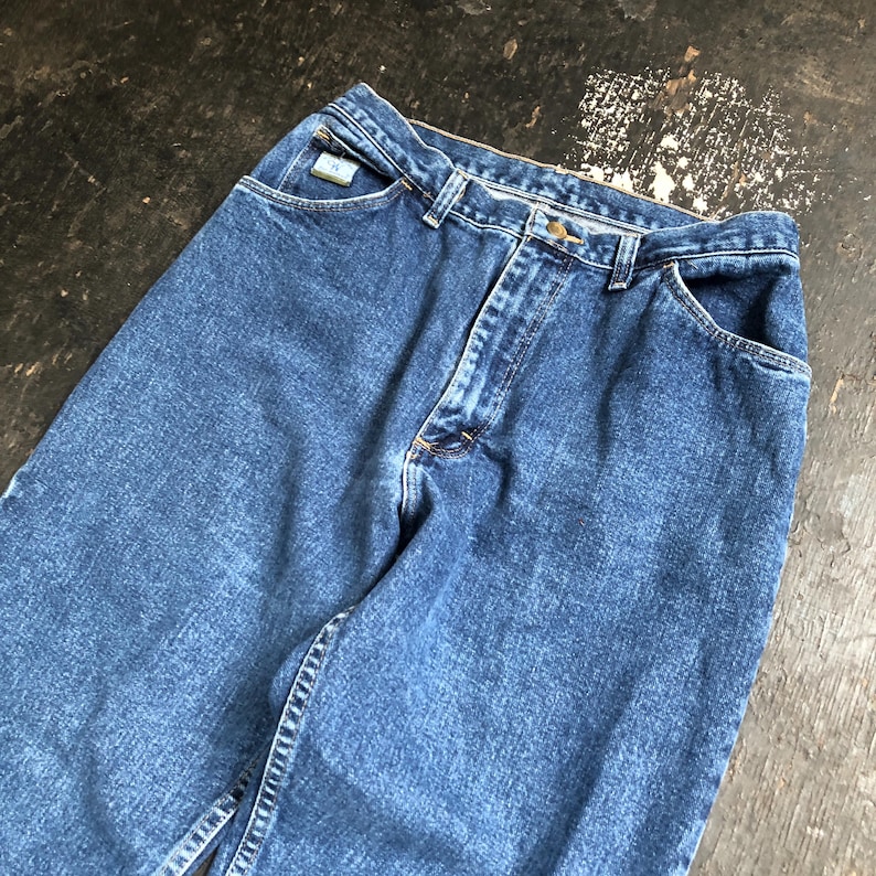 Op de afbeelding: Een spijkerbroek van blauwe denim. De jeans heeft een klassiek ontwerp met vijf zakken, een knoop- en ritssluiting en een kleine logopatch op de voorzak. De denim heeft een medium wassing met subtiele vervaging.