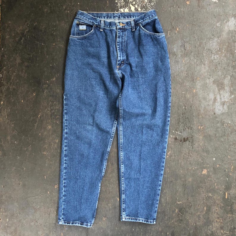 Op de afbeelding: Blauwe spijkerbroek met een klassiek ontwerp met vijf zakken. De jeans heeft een knoop- en ritssluiting, riemlussen en een kleine logopatch op de achterzak. De jeans heeft een medium wassing en lijken vintage te zijn.