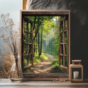 Op de afbeelding: Een ingelijste kunstdruk met een bosscène met een kronkelend pad. Het raamkozijn is van donker hout en het uitzicht toont een zonovergoten pad door groene bomen. Een heldere glazen vaas met gedroogde bloemen en een houten lantaarn met een kaars staan op de voorgrond.