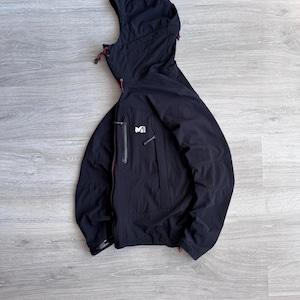 May include: Black hooded jacket with a full-length zipper and a small logo on the chest. The jacket has red accents on the zipper pulls and hood drawstrings. The jacket is made of a lightweight material.
