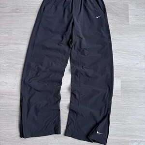Puede incluir: Pantalones deportivos negros con el logotipo blanco de Nike. Los pantalones tienen cintura el&aacute;stica, bolsillos laterales y cremalleras en los tobillos. Fabricados con material ligero.