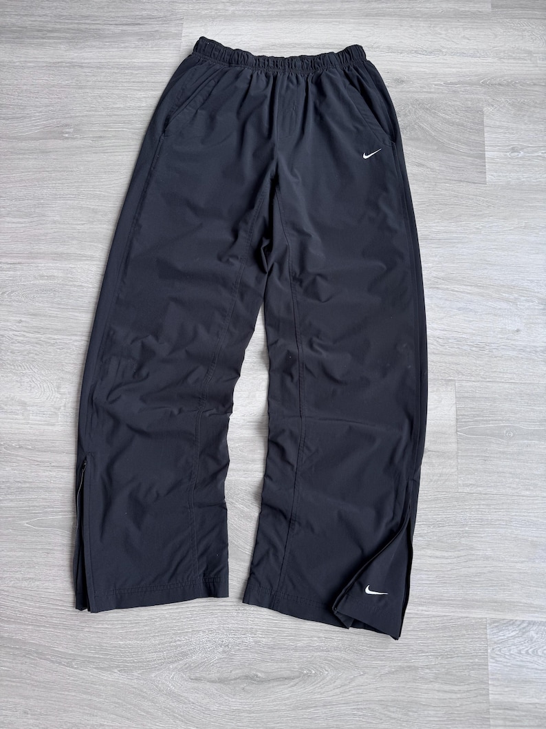 Puede incluir: Pantalones deportivos negros con el logotipo blanco de Nike. Los pantalones tienen cintura el&aacute;stica, bolsillos laterales y cremalleras en los tobillos. Fabricados con material ligero.