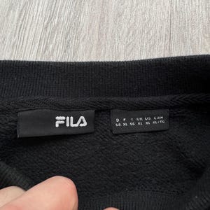 Peut inclure: Sweat-shirt noir &agrave; col rond avec une &eacute;tiquette FILA. L'&eacute;tiquette comprend des informations de taille : D 54, F XL, I XL, UK XL, US XL, CAN XL/TG.