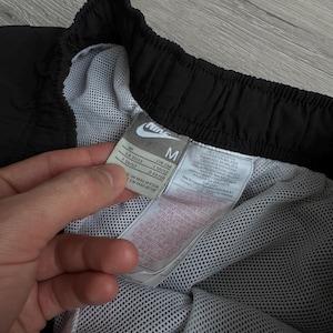 Puede incluir: Pantalones cortos deportivos negros con forro de malla blanca. Los pantalones cortos tienen un logotipo de Nike y una etiqueta de talla M. La etiqueta incluye informaci&oacute;n de tallas.