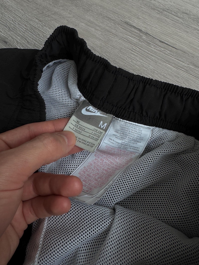 Puede incluir: Pantalones cortos deportivos negros con forro de malla blanca. Los pantalones cortos tienen un logotipo de Nike y una etiqueta de talla M. La etiqueta incluye informaci&oacute;n de tallas.