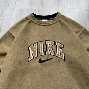 May include: A white ceramic mug with a black handle and the text "But First, Coffee" in a black, handwritten-style font. The mug is on a white surface.