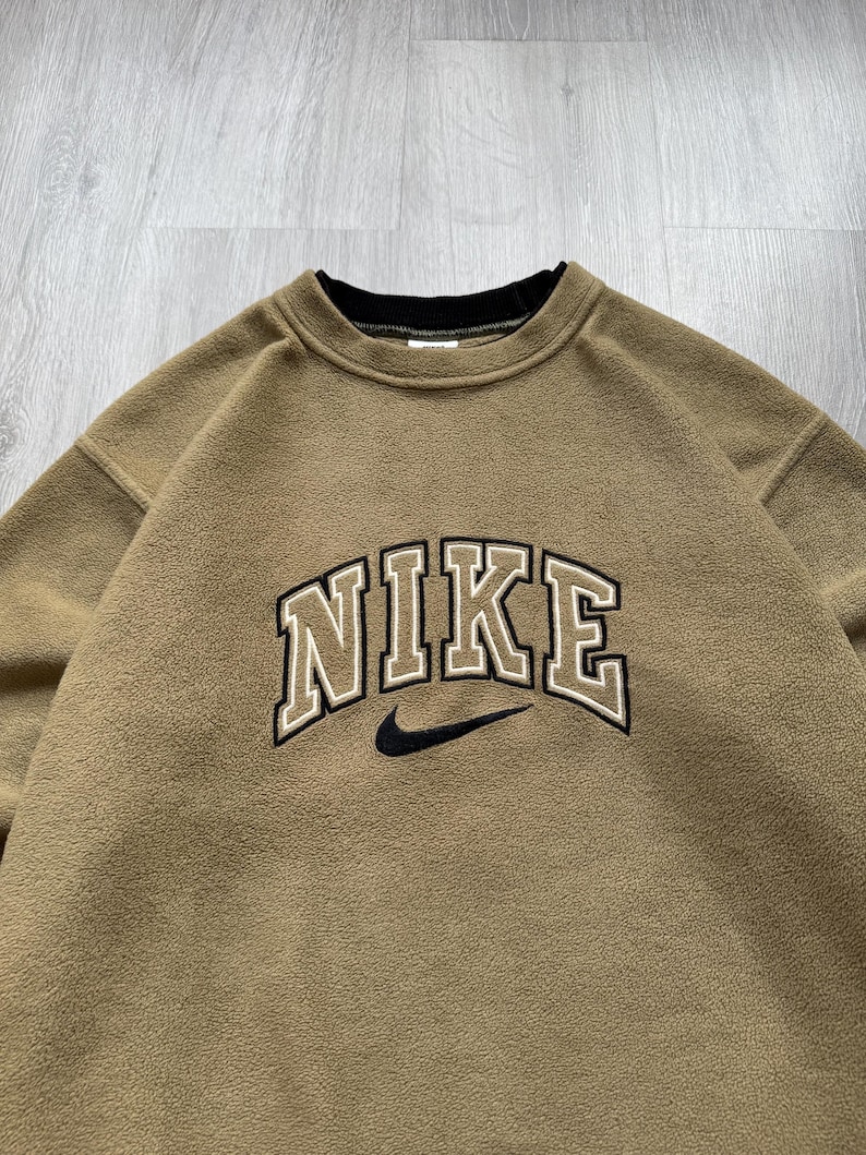 May include: A white ceramic mug with a black handle and the text "But First, Coffee" in a black, handwritten-style font. The mug is on a white surface.