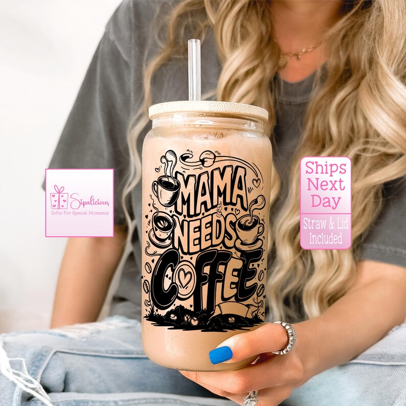 May include: A clear glass jar with a bamboo lid and a black and white graphic that says "Mama Needs Coffee". The jar is filled with a light brown liquid and has a straw sticking out of the top.