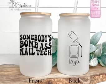 May include: White frosted tumbler with a black design that says "Somebody's Bomb Ass Nail Tech". The back of the tumbler has a black and white illustration of a nail polish bottle and the name "Kayla".