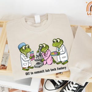 May include: A white ceramic mug with a black handle and the text "But First, Coffee" in a black, bold font. The mug is on a white surface.