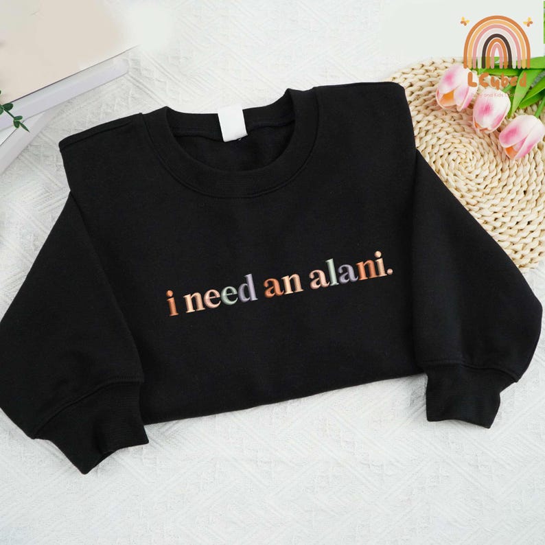 May include: Black sweatshirt with the text "i need an alani." in rainbow colors.