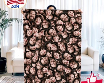 May include: A large, rectangular blanket featuring a repeating pattern of smiling faces. The faces are a mix of men and women with various hairstyles and expressions. The blanket is held up in front of a white couch and curtains.