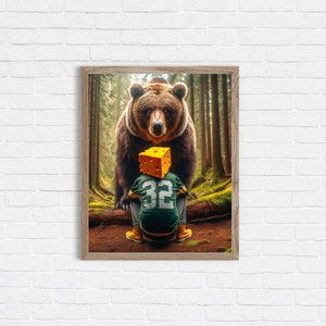 Puede incluir: Impresión artística enmarcada que representa un oso pardo en un bosque. Delante del oso, una persona lleva una camiseta de fútbol verde y dorada con el número 32 y una cabeza de bloque de queso amarillo.