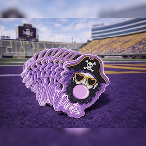 May include: A stack of purple stickers featuring a pirate with a beard, heart-shaped sunglasses, and a bubblegum bubble. The pirate wears a hat with a skull and crossbones. The word "Pirates" is written in cursive.