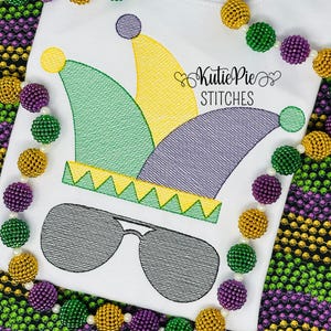 May include: A white t-shirt with an embroidered green, yellow, and purple jester hat with sunglasses. The shirt is surrounded by a beaded garland of purple, green, and gold beads.