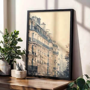 May include: A framed vertical wall art print featuring a sepia-toned architectural scene of multi-storey Parisian-style buildings with wrought iron balconies, chimneys, and tall windows, set against a soft, hazy, light-coloured sky background.