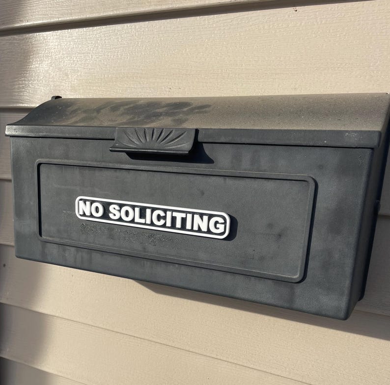 May include: A black mailbox with a white sign that reads "NO SOLICITING".
