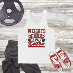 May include: White tank top with a red and black graphic of a skeleton lifting weights. The graphic says "Weights Before Dates" and "Progression Over Everything".