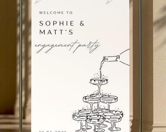 May include: White sign with black text announcing "Welcome to Sophie & Matt's engagement party" with a date of 12.06.2025. A black and white illustration of champagne glasses stacked in a pyramid with a bottle pouring champagne into the top glass.