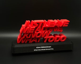 Puede incluir: Escultura 3D roja de la frase "Just leave me alone I know what to do" sobre una base negra con el texto "Kimi Räikkönen 2012 Abu Dhabi Grand Prix".