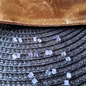 Peut inclure: Gros plan sur une surface tissée noire avec des perles de verre transparentes éparpillées. Les perles sont petites et de forme carrée.