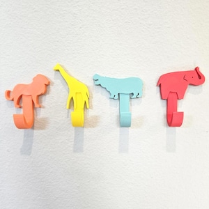 May include: Four colorful animal-shaped wall hooks. The hooks are shaped like a lion, giraffe, hippo, and elephant. The lion is orange, the giraffe is yellow, the hippo is light blue, and the elephant is red. Each hook has a curved bottom for hanging items.