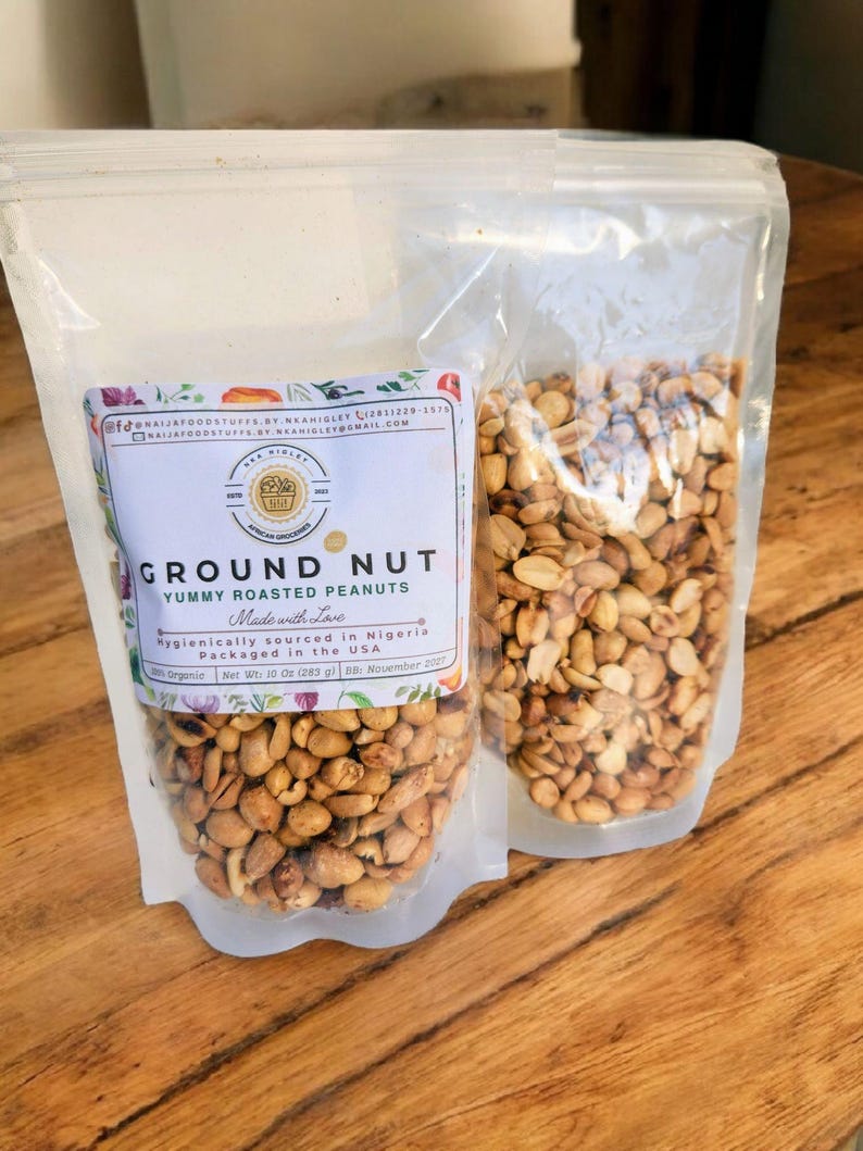 Puede incluir: Dos bolsas de pl&aacute;stico transparentes llenas de cacahuetes tostados. Las bolsas est&aacute;n etiquetadas con "GROUND NUT YUMMY ROASTED PEANUTS" y "Made with Love". El texto tambi&eacute;n dice "Hygienically sourced in Nigeria" y "Packaged in the USA".