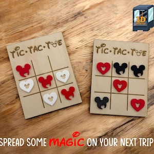 May include: Two wooden Tic-Tac-Toe boards with red, white, and black heart-shaped game pieces. The boards have the text "Tic-Tac-Toe" and a Mickey Mouse-inspired design. The phrase "Spread some magic on your next trip!" is also visible.