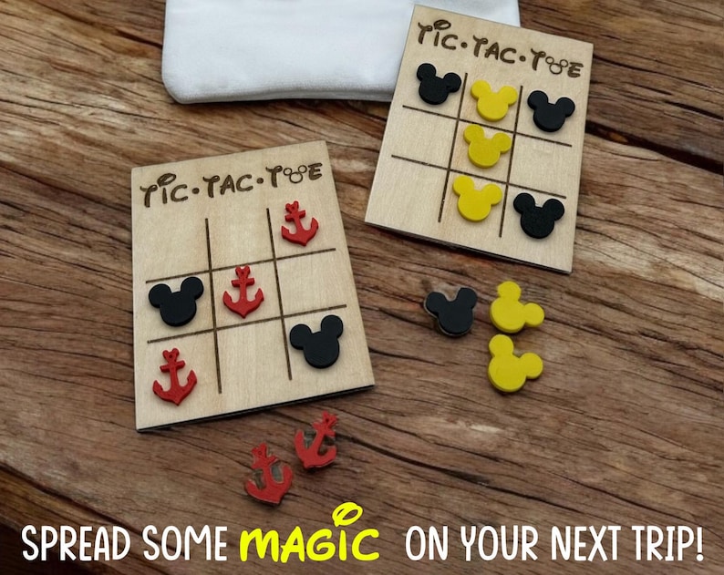 A wooden tic-tac-toe game board with red anchor and black Mouse head game pieces inspired for your next cruise. The board has the words 'Tic-Tac-Toe' written on it. The phrase "Spread some Magic on your Next Trip" is written on the bottom of the photo.
