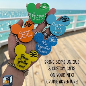 May include: Five colorful 3D printed keychains shaped like mouse heads, each featuring a unique design and text. The keychains are green, orange, light blue, dark blue, and yellow. Text includes Alaska 2026, Halloween on the High Seas, Custom Text Here, My Favorite Place, and Best Cruise Ever.