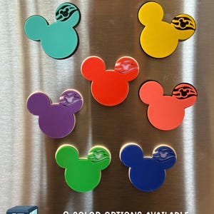 May include: Nine 3D printed Mickey Mouse head magnets in various colors, including teal, yellow, red, purple, coral, green, and blue. Each magnet features a black and white design of a cruise ship's wave.