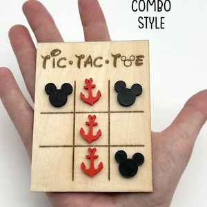 A cruise line inspired wooden tic-tac-toe board with black Mouse heads and red anchors as game pieces. The board has the words 'Tic-Tac-Toe' written on it. The text 'MOUSE / ANCHOR COMBO STYLE' is written above the board.