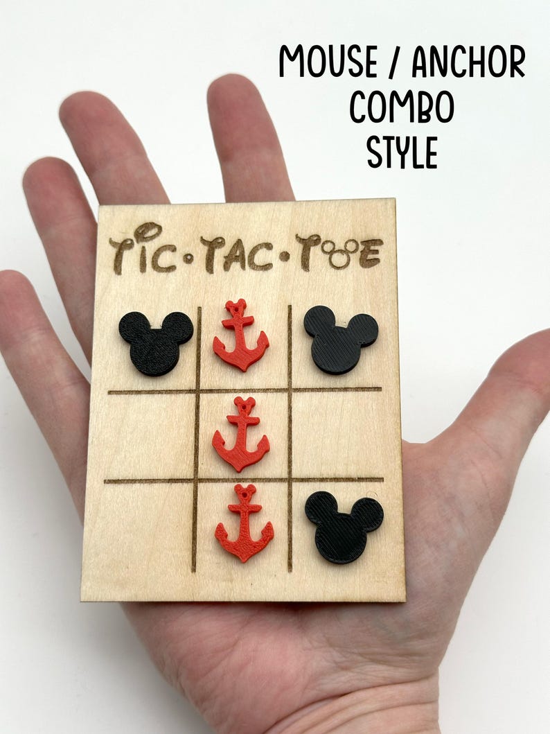 A cruise line inspired wooden tic-tac-toe board with black Mouse heads and red anchors as game pieces. The board has the words 'Tic-Tac-Toe' written on it. The text 'MOUSE / ANCHOR COMBO STYLE' is written above the board.
