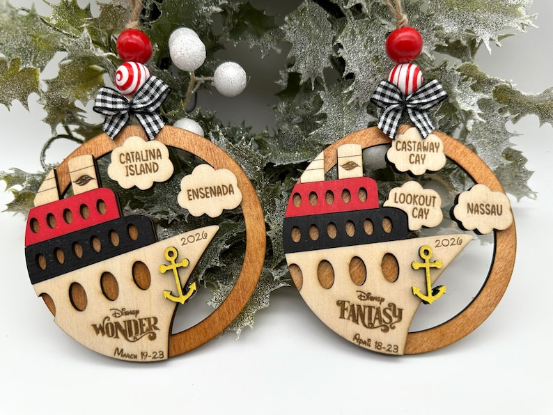 2 wooden ornaments with a boat image painted in red, black and natural wood colors. The boat features a DCL ship logo, dates of the cruise and the DCL logo. It also has a anchor painted in yellow on top of the boat. The right side of the ornaments feature clouds with port locations. The left ornament shows 2 port locations and the right image shows 3 port locations. Both ornaments have 2 colored wood beads, a black and white mini fabric bow and twine for hanging on top of the ornament.