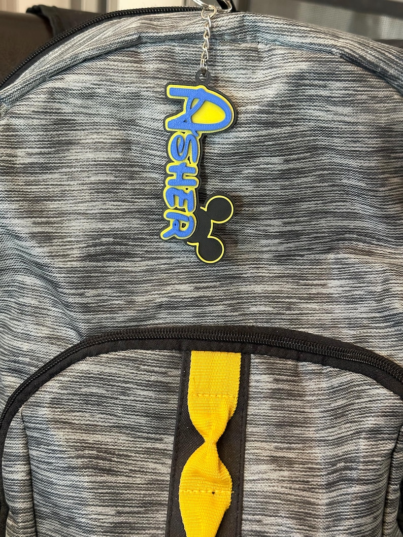 An example of a boy keychain hanging off a backpack. The keychain is attached to the zipper of the backpack.