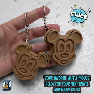 May include: Two light brown 3D printed keychains shaped like a cartoon mouse head with a waffle-like texture. Each keychain features a metal split ring and chain. Text on the image reads: CLICK and YOUR FAVORITE WAFFLE MOUSE READY FOR YOUR NEXT TRAVEL ADVENTURE GIFTS!