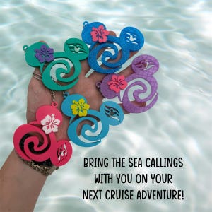 May include: A hand holds several colorful Mickey Mouse-shaped keychains. Each keychain features a floral accent and a unique color: pink, teal, blue, purple, and light blue. The keychains are displayed against a backdrop of rippling water. Text on the image reads: "BRING THE SEA CALLINGS WITH YOU ON YOUR NEXT CRUISE ADVENTURE!"
