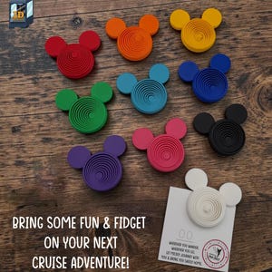 May include: A collection of ten 3D-printed fidget toys shaped like mouse heads with concentric circular patterns in red, orange, yellow, green, teal, blue, purple, pink, black, and white. One white toy is attached to a card with printed text.