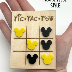 Mouse Inspired Tic-Tac-Toe game board with yellow and black Mouse head pieces. The board is made of wood and has a natural wood finish. The game board has the words 'Tic-Tac-Toe' written on it.