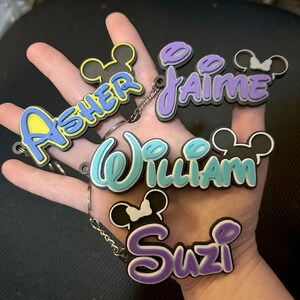 4 Personalized Mouse Inspired Name Keychains in various colors. 2 girl versions and 2 boy versions are shown for examples. The keychains will have a mouse head included for the boy option and girl versions will have a bow included.